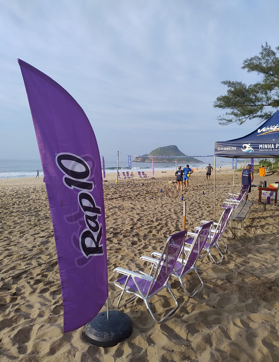 Bandeira RAP10 e cadeiras de praia na areia