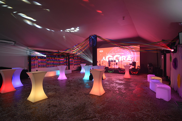 Área de integração com mesas iluminadas e decoração de Carnaval